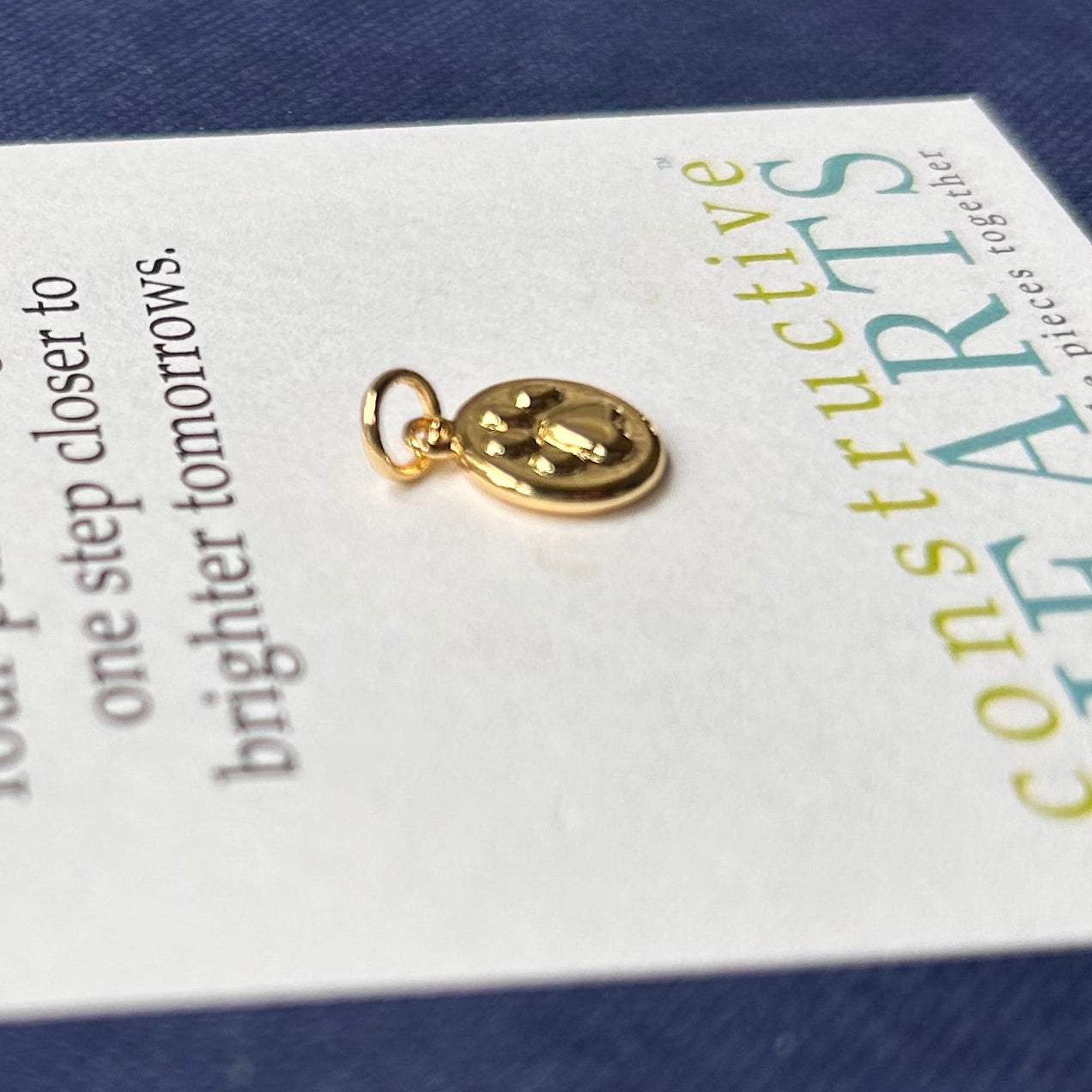 Gold filled embossed paw on circle charm.