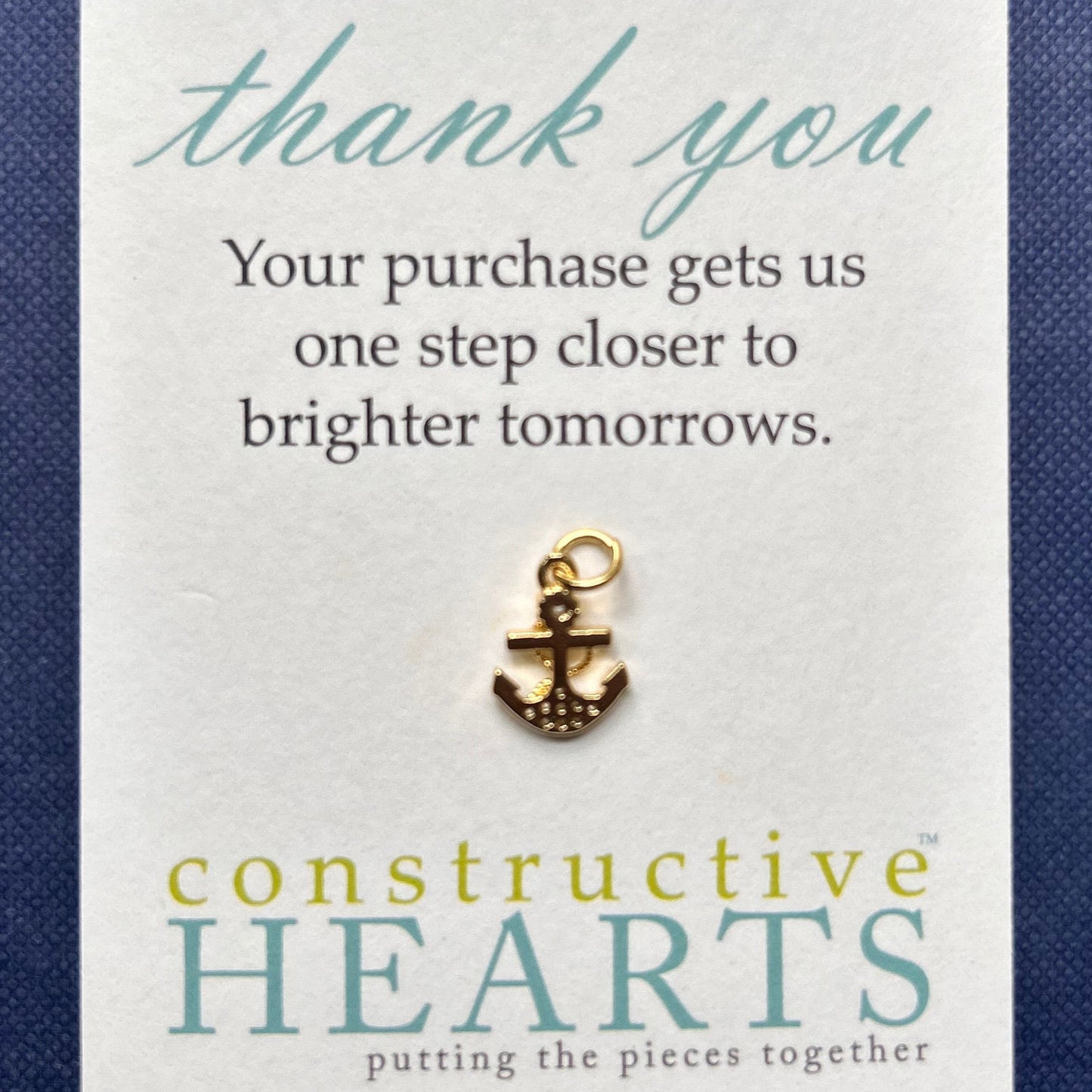 Card with pave anchor charm and 'Constructive Hearts' branding on a blue background.
