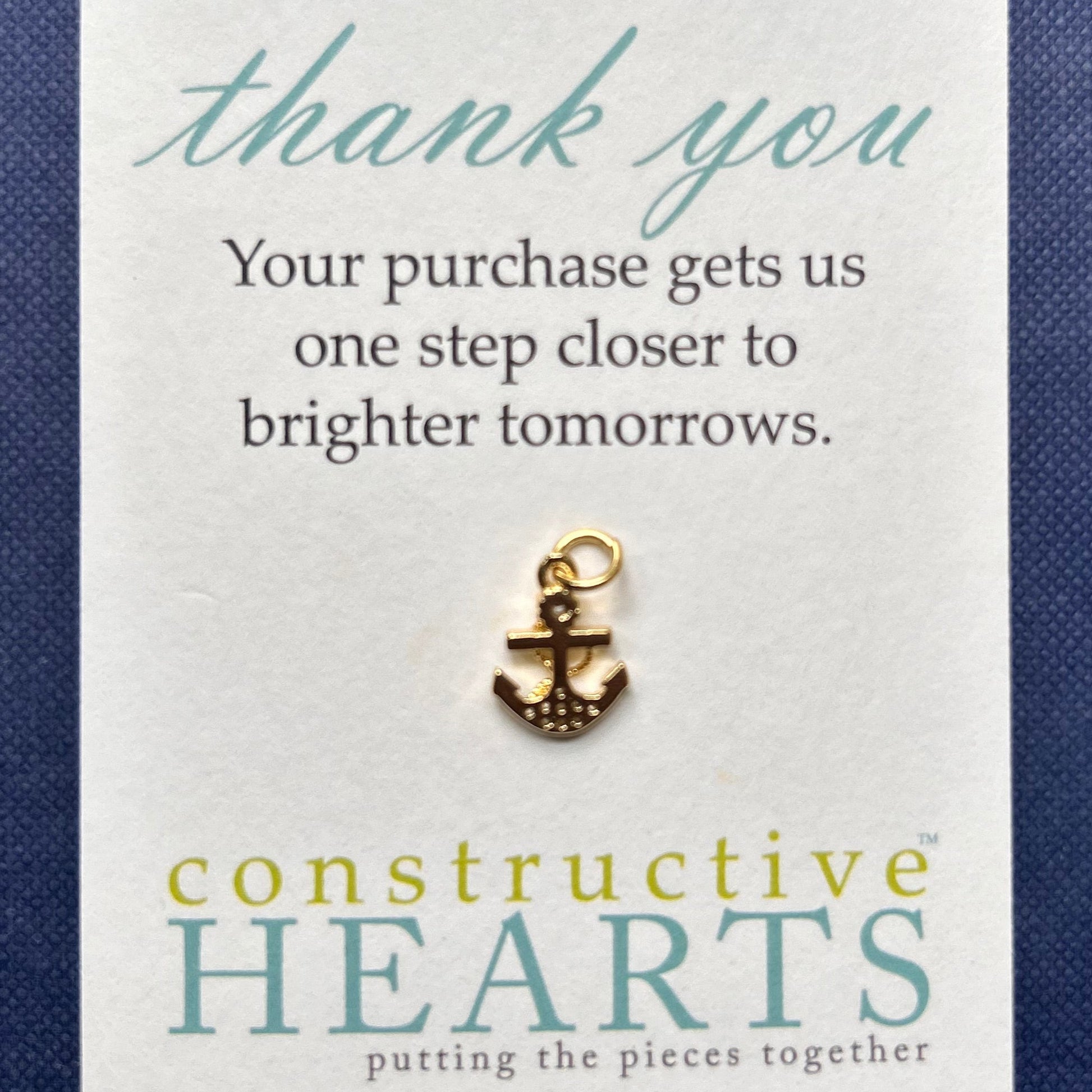 Card with pave anchor charm and 'Constructive Hearts' branding on a blue background.
